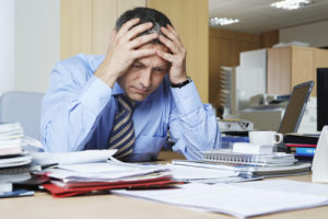 man holding head due to stress from work