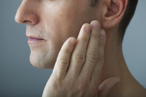 man touching jaw due to TMJ pain looking for Macomb treatment