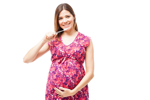 woman holding a toothbrush and taking care of her teeth during pregnancy