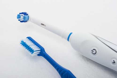 Traditional Manual and Electric Toothbrush Together Over White