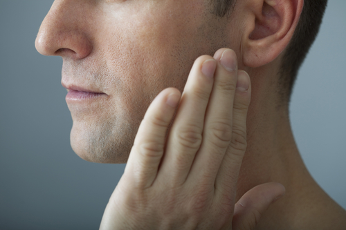 man holding sore jaw in need of macomb tmj treatment