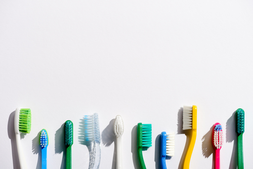 a line of different colored toothbrushes on white background
