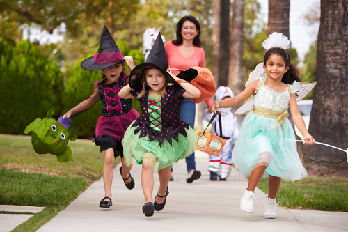 mom taking children trick or treating on halloween