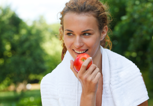 Young woman after sport workout eating apple