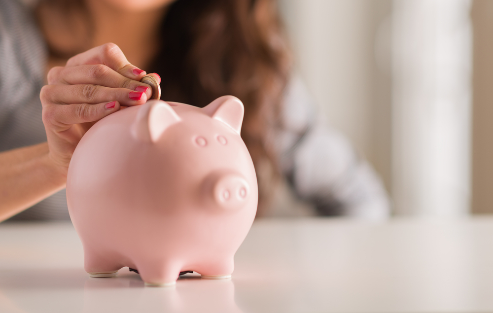 woman putting money into ceramic piggy bank