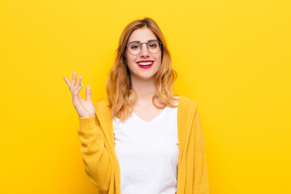 young woman smiling against yellow background