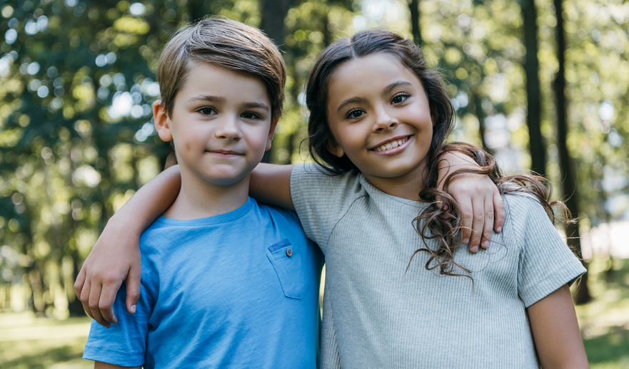 young boy and girl smiling with forest background