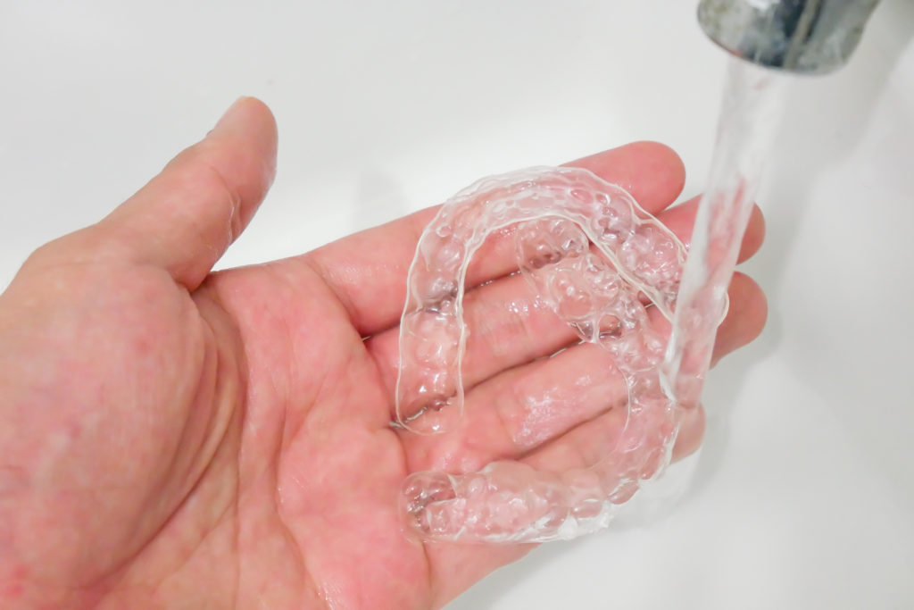 Invisalign Aligners being rinsed with water to clean