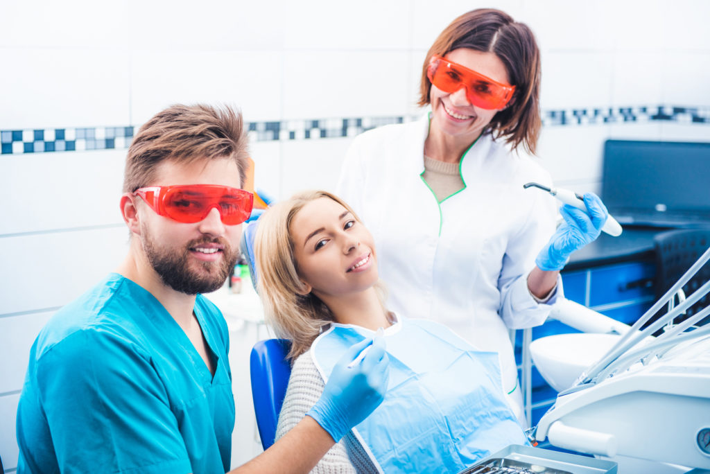 Dentists treating patient with laser technology