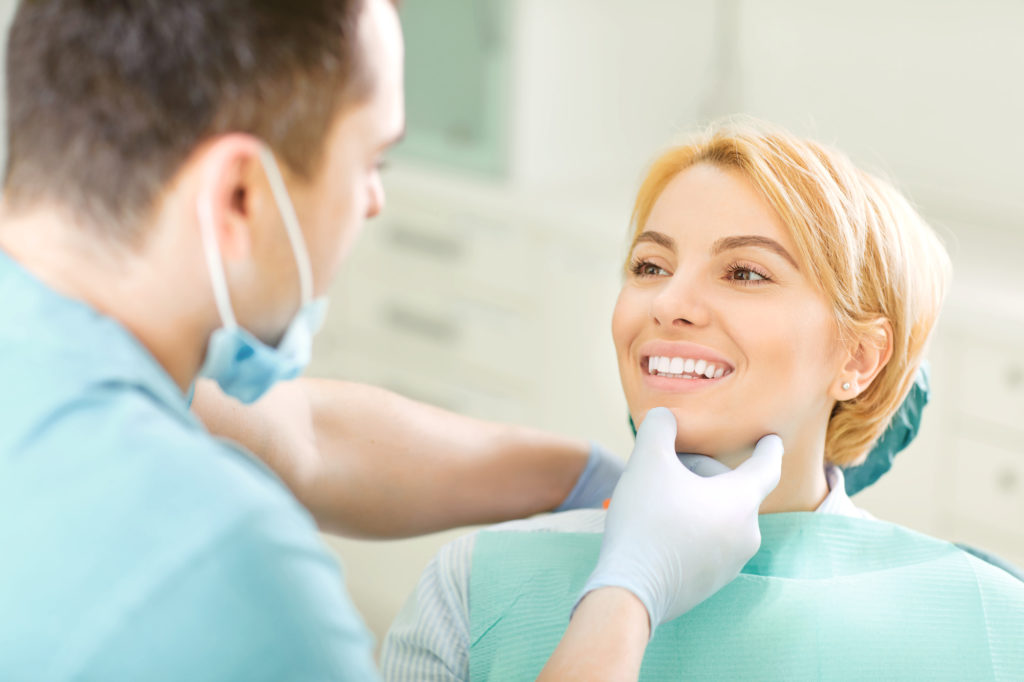 Dentist and patient looking at healthy teeth and smiling. 