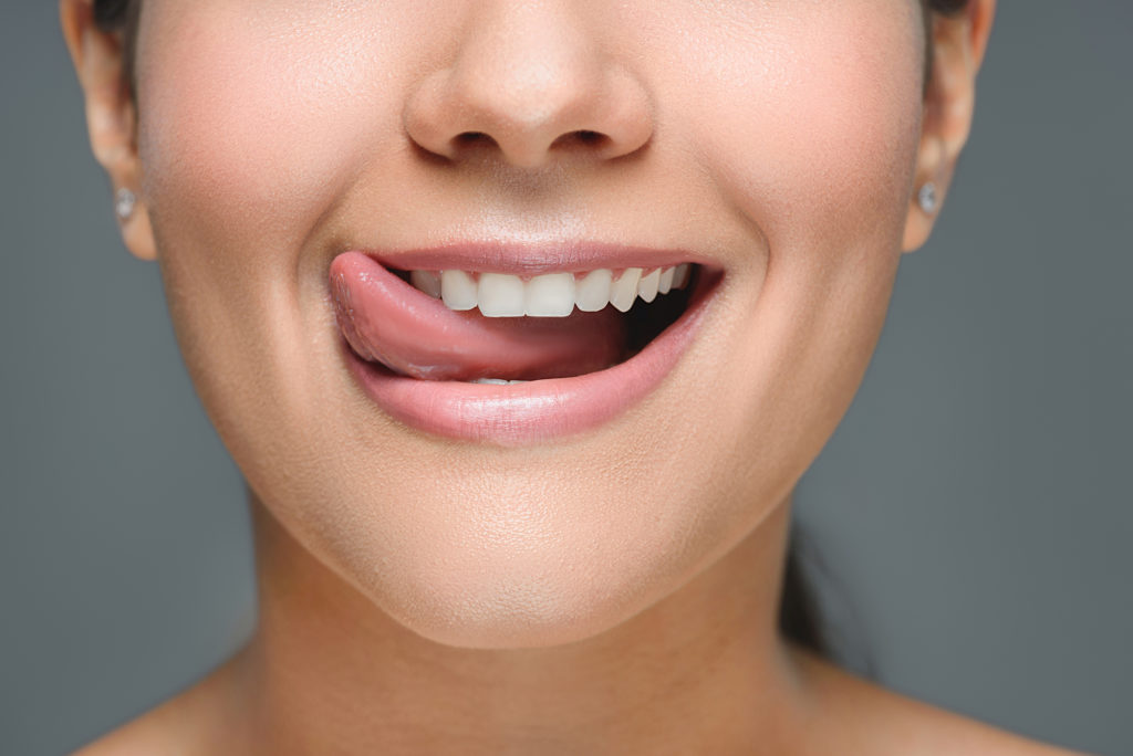 Woman with white teeth sticking out her healthy tongut