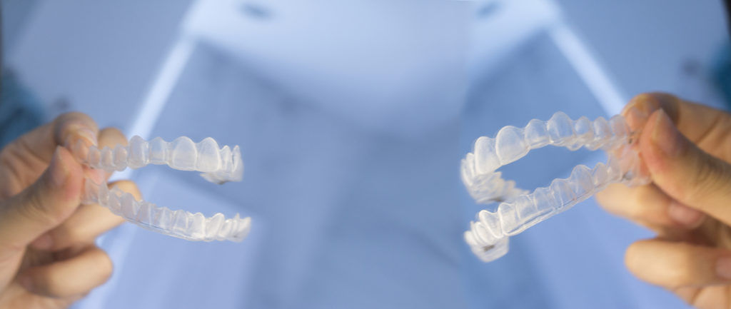 Woman hand comparing Invisalign clear aligners.