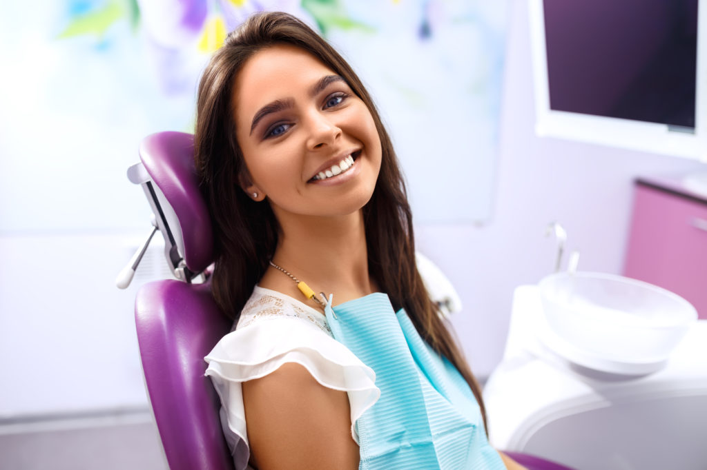 Happy patient at modern dentist office. 