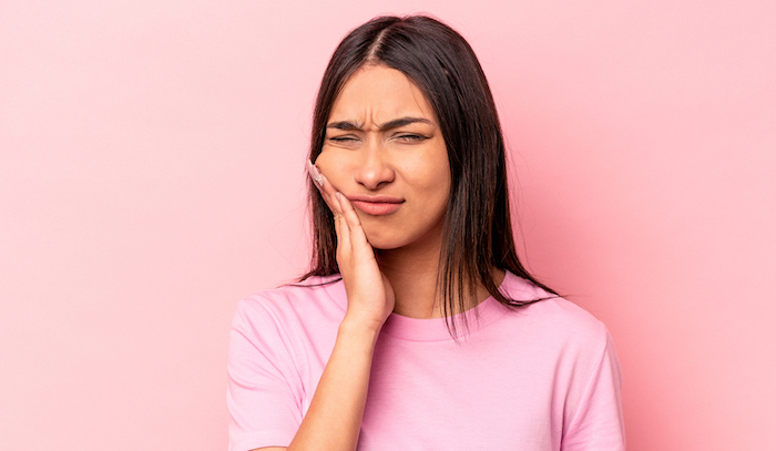 woman touching her cheek due to tooth pain