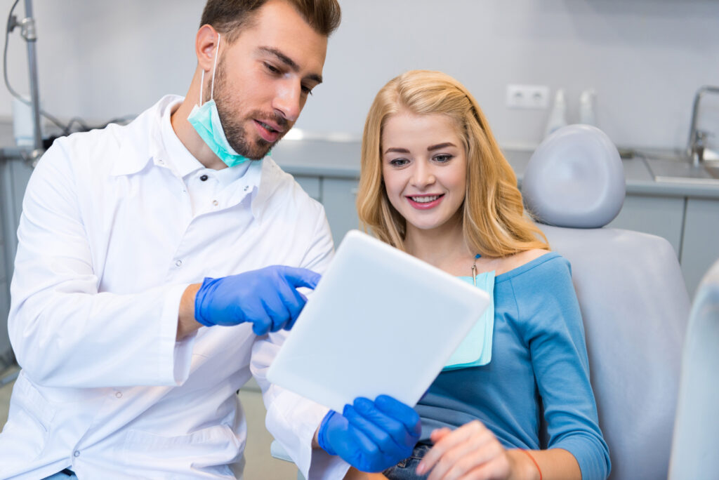 Modern dentist showing patient new dental technology. 