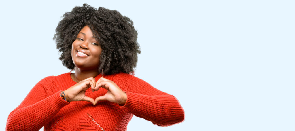 Beautiful woman with healthy teeth making a heart with her hands. 