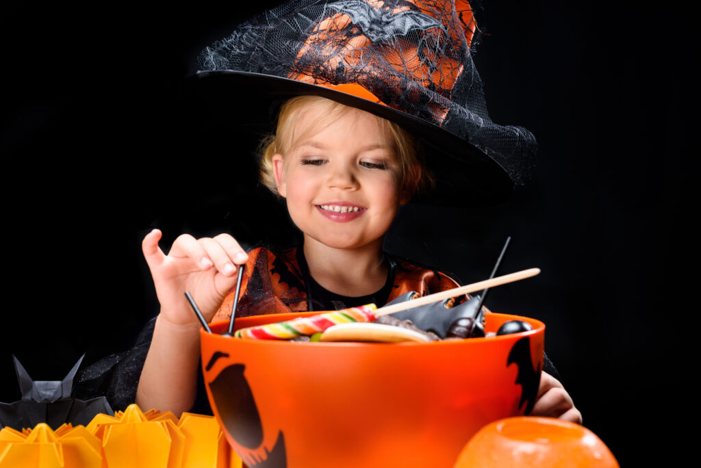 Child with healthy teeth choosing Halloween treats. 