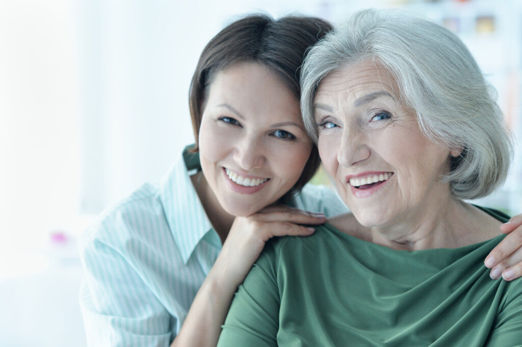 Mother and daughter with healthy teeth smiling together. 