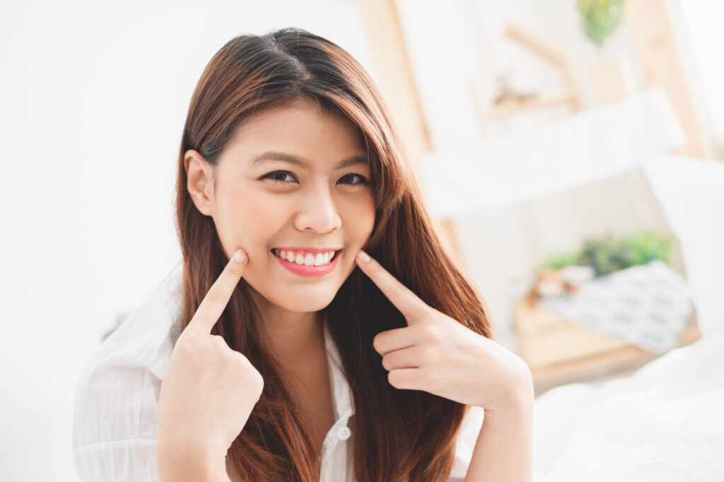 Woman pointing to healthy teeth. 