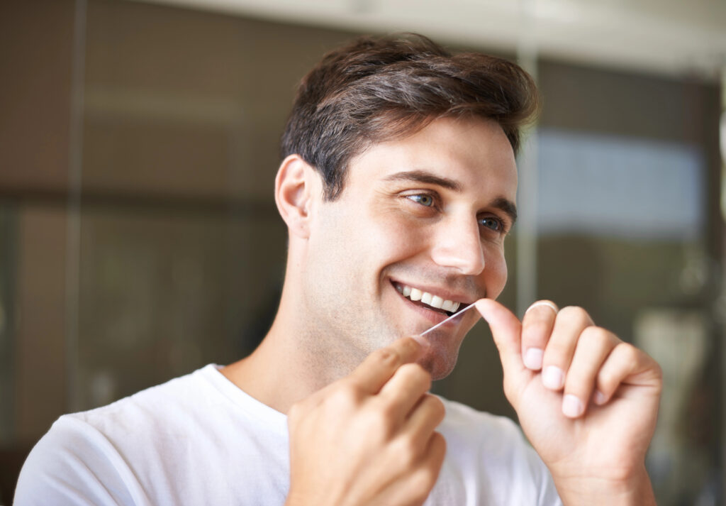 Young man with healthy smile flossing. 